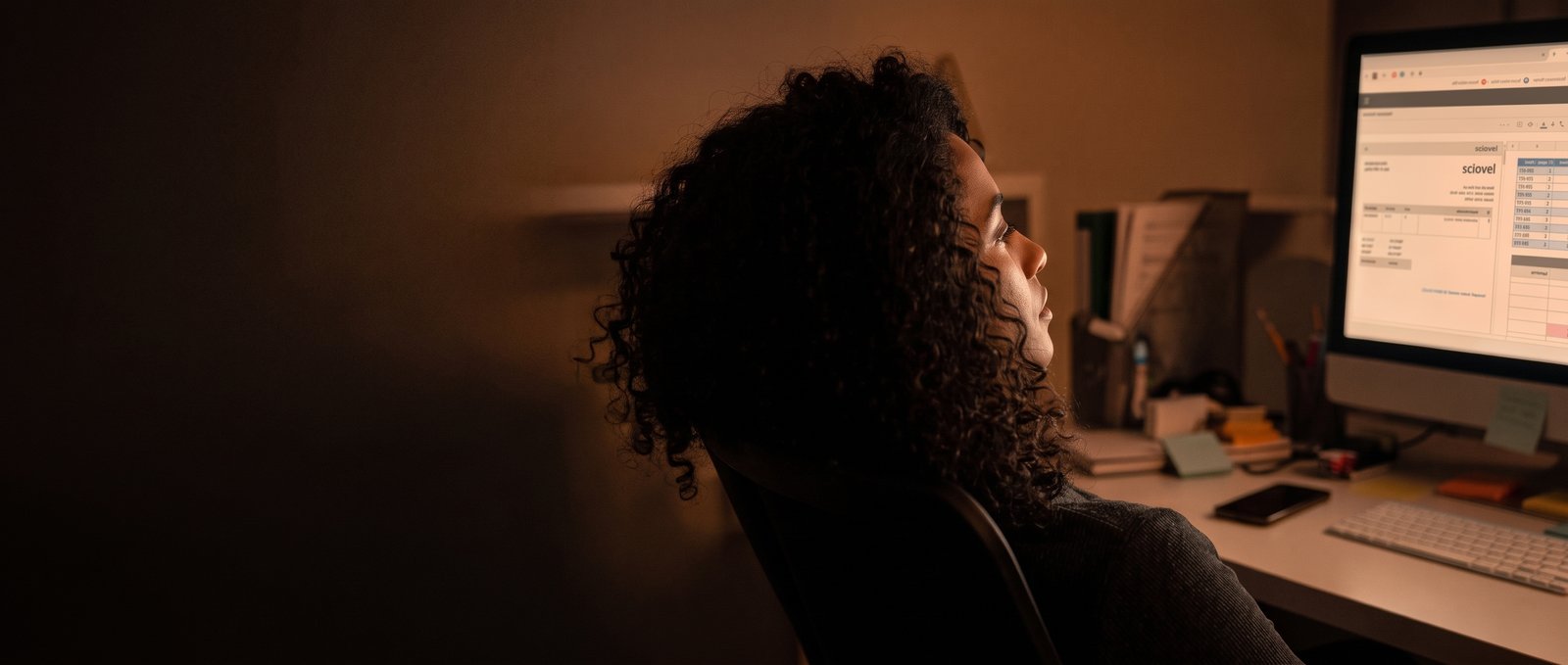Small business owner at her desk late at night, overwhelmed by everything on her to-do list